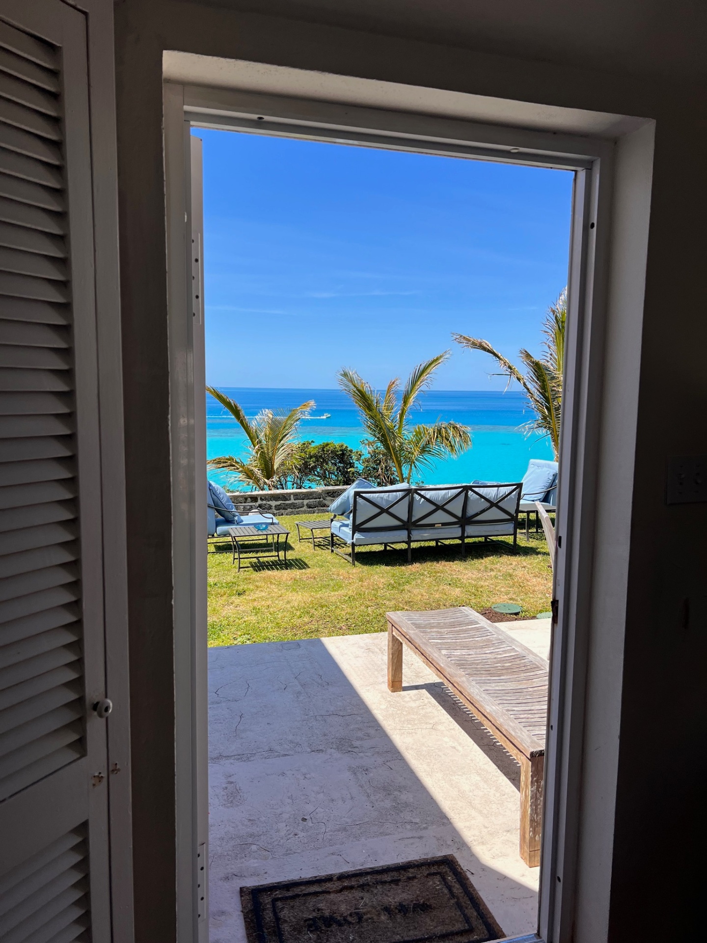 Ocean view through doorway with outdoor furniture and palm trees